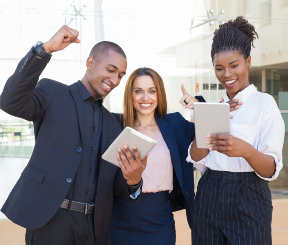 Cheerful business colleagues with tablets rejoicing at team success. Happy business man and women looking at tablet screen and making winner gesture. Successful teamwork concept